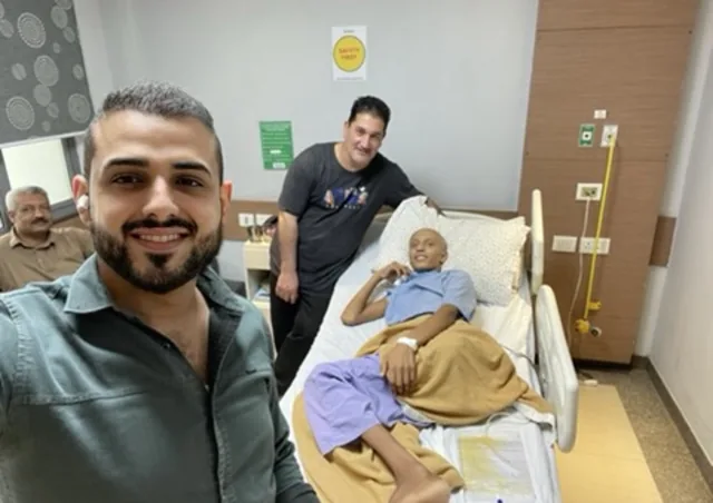 مريض شاب مبتسم على سرير المستشفى وحوله مرافقون في الهند